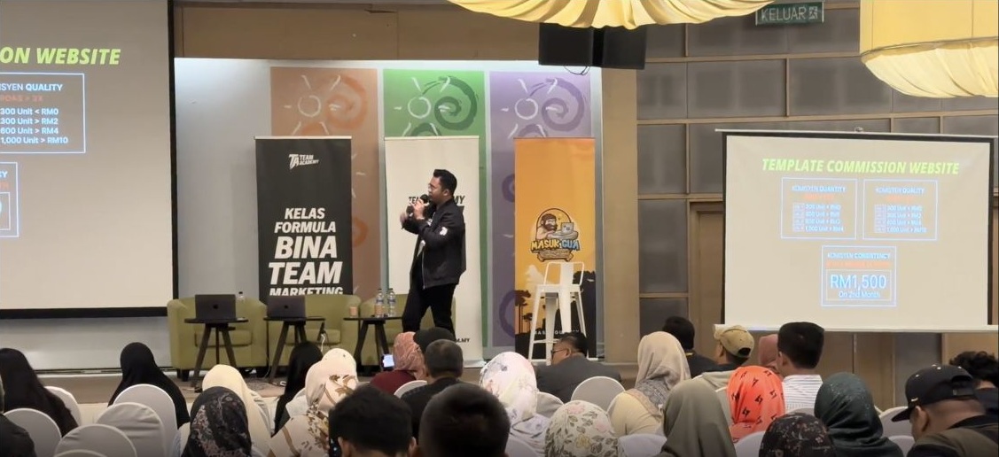 Akram memegang mikrofon semasa berkongsi di pentas Formula Bina Team Marketing