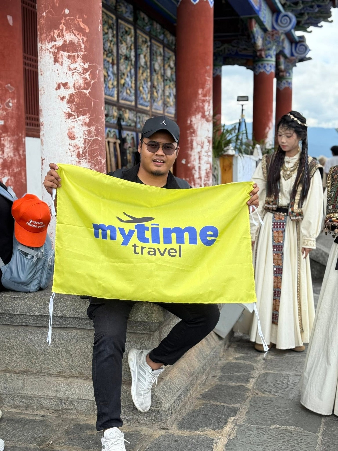Akram membawa bendera MyTime Travel ketika di lokasi perjalanan